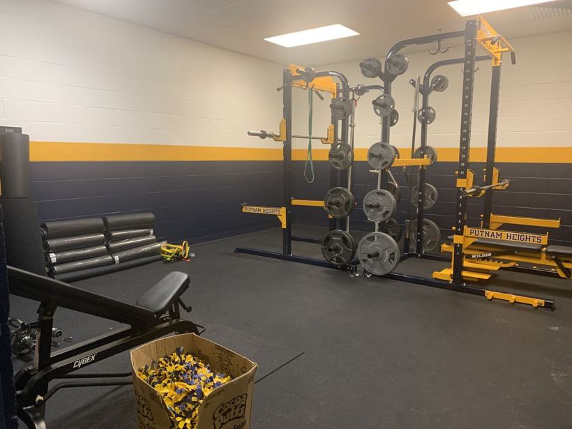 Weight room with navy and gold racks and benches.