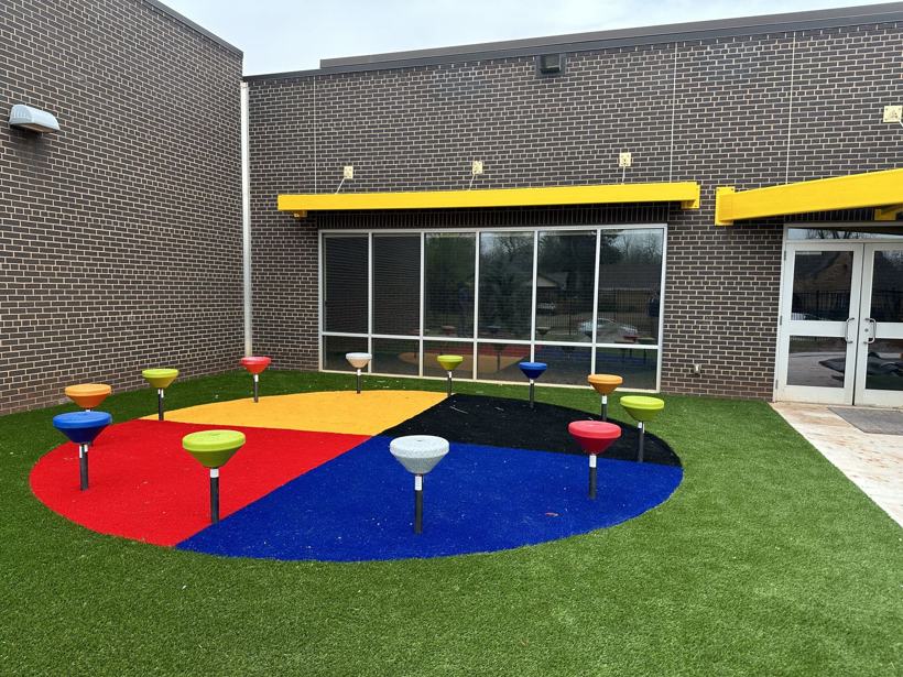 Outdoor classroom with a color-quadrant turf circle and spinner seats.