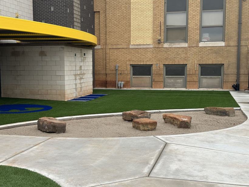 Stone seating ring around a sand court.