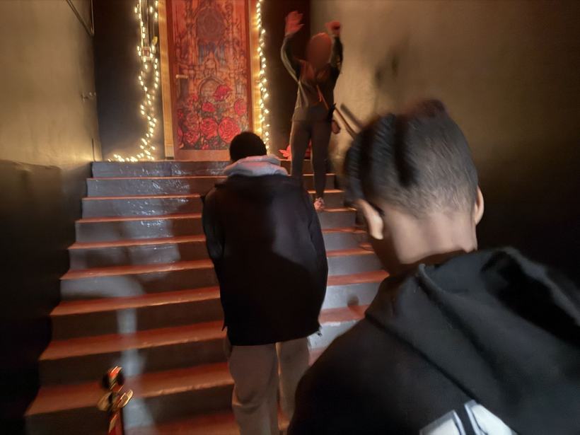 Students climbing a lit stairway toward the house reveal. Faces blurred.
