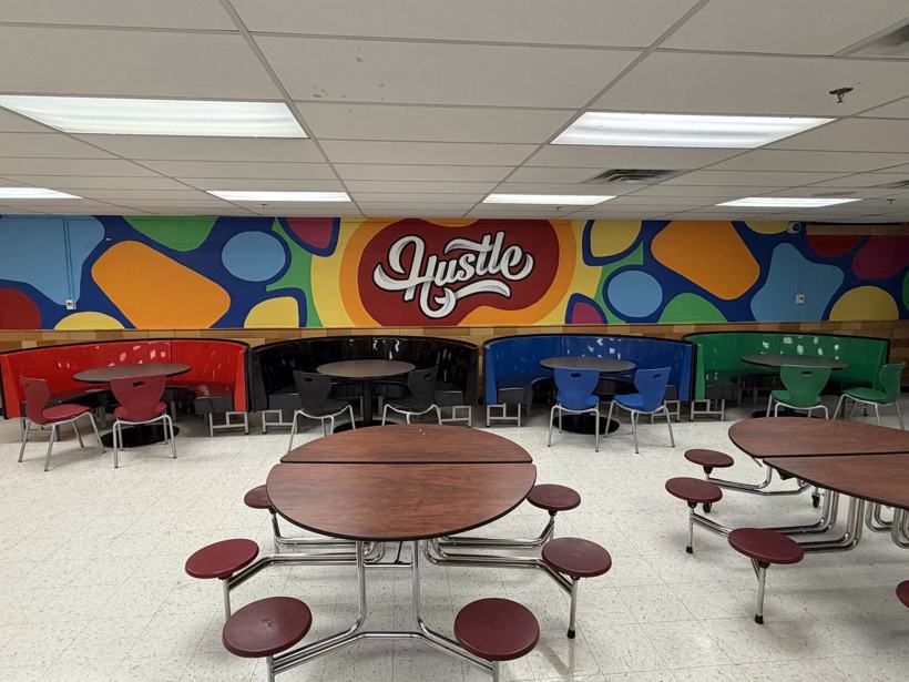 Wide view of the Hustle mural over a row of booths.