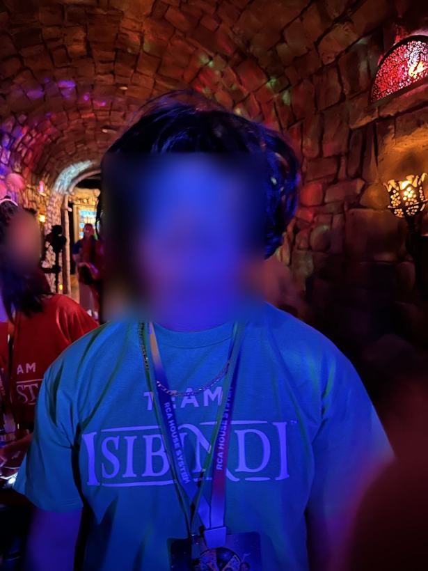 Student in a party wig and shutter shades. Face blurred.